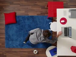 MS, Lockdown, man lying down in office, suddenly checking his computer, overhead view Stock Footage