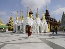 WS Shot of monk walking in front of white temple in shwedagon pagoda / Yangon, Yangon Division, Myanmar Stock Footage