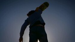skater standing in sunlight raising hands looking happy with sun flares silhouette venice California skatepark Stock Footage