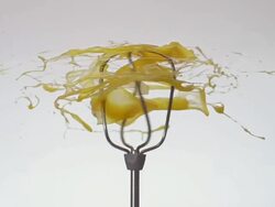CU SLO MO Shot of egg yolk getting smashed while falling into spinning hand mixer / Munich, Bavaria, Germany Stock Footage