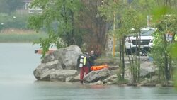 Police diver getting help donning wet suit in the rain Stock Footage