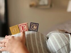 A pregnant women using blocks to spell the month of DEC on her stomach. Stock Footage