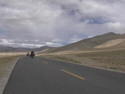Long shot bike passing on highway Taklakot Tibet China Stock Footage