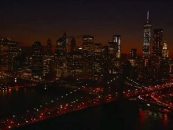 Aerial -At night, a low pass over the Manhattan and Brooklyn bridges with a tilt up to reveal the Freedom Tower, then wrapping around lower Manhattan to the Staten Island Ferry terminal. Stock Footage