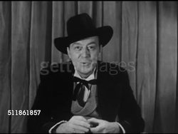 1952: 19th CENTURY GAMBLER: 'Jack O'Diamonds' character dressed in historic, professional gambler clothing, sitting at poker table flipping cards w/ hands while explaining who he is & giving clue to what he does for living. Instructional Video