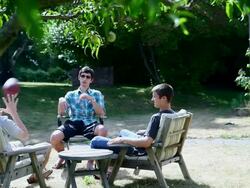MS Three male friends sitting outside in circle throwing football to each other/Washington, USA Stock Footage