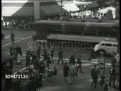 1939: U.S. CITIES & TOWNS: VS City skyscrapers, crowded street intersection, traffic on highway, town streets, woman leaving grocery store. INT VS Butcher shop, grocery store clerk & customer. Lifestyle Instructional Video