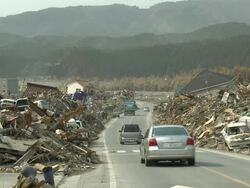 Car drive along road bulldozed clear of deris through remains of Rikuzentakata city, Iwate Prefecture, Japan on 2nd April 2011; 3 weeks after the tsunami following the Tohuku earthquake of March 2011. Stock Footage