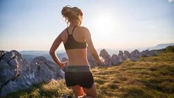 Young female athlete running on a meadow in the mountains Stock Footage