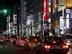 MS Shot of Street crossing with cars and taxis passing through up scale area at night / Tokyo, Japan Stock Footage