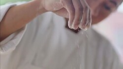 Baker sprinkles flour on dough with her hands Stock Footage