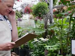 Worker ordering inventory in plant nursery greenhouse Stock Footage