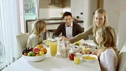 Mom bringing pancakes to her family sitting at the table Stock Footage