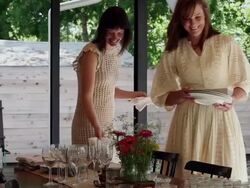 MS PAN two sisters in discussion smiling setting table for dinner on front porch of home Stock Footage