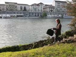 Boom as businessman descends path,removes tablet, city behind Stock Footage