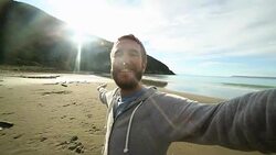 Young man takes selfie portrait on New Zealand's beach Stock Footage