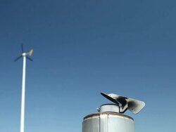 Smokestack and Wind Turbine against a Blue Sky Stock Footage