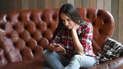 Young beautiful woman using smartphone sitting on sofa Stock Footage