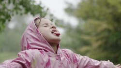 Young girl catching the rain on her tongue Stock Footage