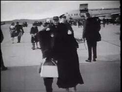 B/W 1960s REAR VIEW woman + child walking quickly to returning soldier / they hug + kiss / CA Stock Footage