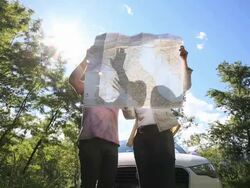 Couple read road map beside car, in green forest Stock Footage