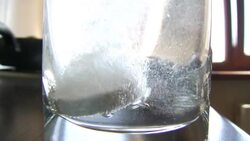 An effervescent pill is dropped into a glass of water. Stock Footage