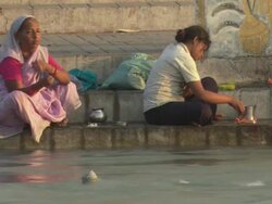 WS Elderly woman and young girl sitting and praying on stone embankment at the Ganges river / Kashi, Uttar Pradesh, India Stock Footage