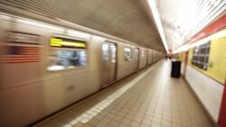 Subway train passes through station as street musician plays acoustic guitar on platform Stock Footage