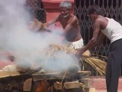 MS TU TD PAN Men laying  dried palm branches on top of  burning body during cremation ceremony AUDIO / Kathmandu, Central Region, Nepal Stock Footage