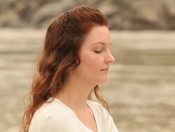Young woman practicing yoga at riverside, Ganges River, Rishikesh, Uttarakhand, India Stock Footage