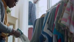 Young shop worker prices shirts with tagging gun in modern clothing store Stock Footage