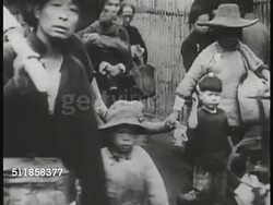 1937: JAPAN ATTACKS CHINA: Chinese people pushed together, moving en mass. Refugees w/ children walking street, child looking up at adult. CU Imperial flag of Japan. Japanese soldiers walking up street, possibly Shanghai. Chinese sitting in rickshaws. Instructional Video