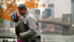 New York couple embrace and kiss passionately in autumn park with Brooklyn Bridge and skyline in background Stock Footage