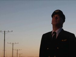 M/S airline pilot watches as airplane passes overhead, early evening Stock Footage