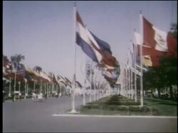 1964 side point of view promenade lined by flags with Unisphere in background at NY World's Fair Stock Footage