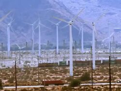 Long lens WS of freight train running along multiple wind turbine generators and automobile traffic on interstate highway 10  / Palm Springs, California, USA Stock Footage