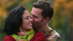 New York couple in love nuzzle on park-bench in Central Park, boyfriend kisses girl on cheek sweetly Stock Footage