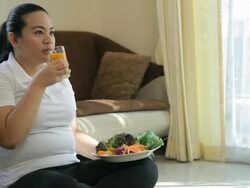 Fat woman drinking orange juice Stock Footage