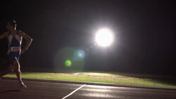 A track athlete passes a baton to his teammate while running in a relay race. Stock Footage