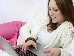 Smiling young woman relaxing using laptop computer, lying on sofa. Stock Footage
