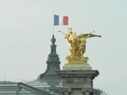 LS  French flag, the tricolor, flying over the Grand Palais with gilded statue on Alexandre III bridge in foreground Stock Footage