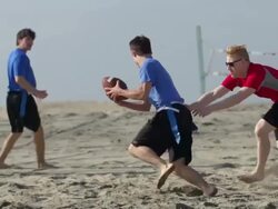 A group of guys playing flag football on the beach. - Slow Motion Stock Footage