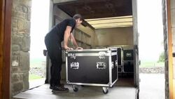 Sound engineer unloads Flight case from the back of a Truck Stock Footage