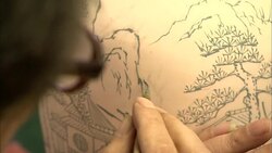 An artist paints a finely detailed design on a piece of pottery. Stock Footage