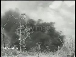 1944: BATTLE OF KWAJALEIN: VS Smoke rising from damaged, burning, structures, thick smoke moving across water. VS Wounded 7th Marine Division soldiers being carried on stretcher, walking. World War II, WWII, Pacific Front Instructional Video