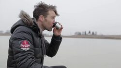 Young man drinking hot tea on frozen pond in winter in rural Montana, USA. Stock Footage