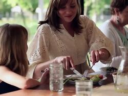 MS TU mother cutting food on daughters plate while dining with family on front porch of home Stock Footage