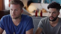 Guys sitting on couch playing video games and cheering Stock Footage