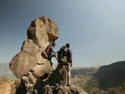 Three rock climbers standing on the cliff of a mountain Stock Footage
