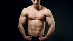 healthy athlete shows good muscle on black background Stock Footage